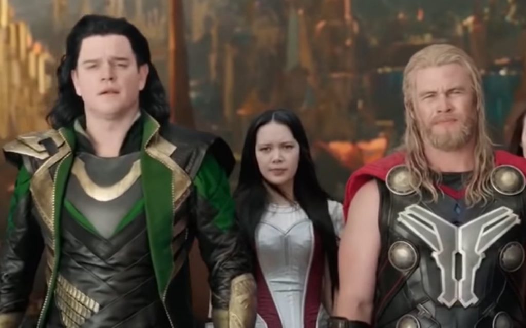 Matt Damon in green and gold attire and Luke Hemsworth in black and gold armor playing stage versions of Loki and Thor in Thor: Ragnarok