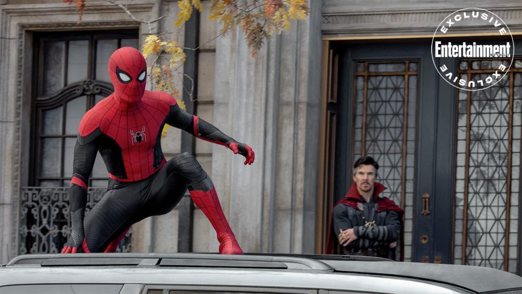 Spider-Man is perched on top of a car as Doctor Strange looks on in the background in Spider-Man: No Way Home