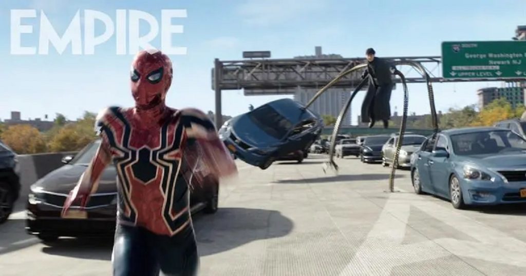 Spider-Man in a red, gold and black costume running away from Doctor Octopus, who is a few feet above the ground with mechanical arms overturning a car on a freeway