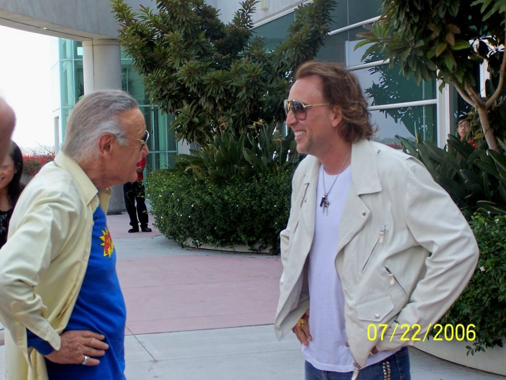 Stan Lee with his hands on his hips talking to Nicolas Cage on the roof of the convention center at San Diego Comic Con 