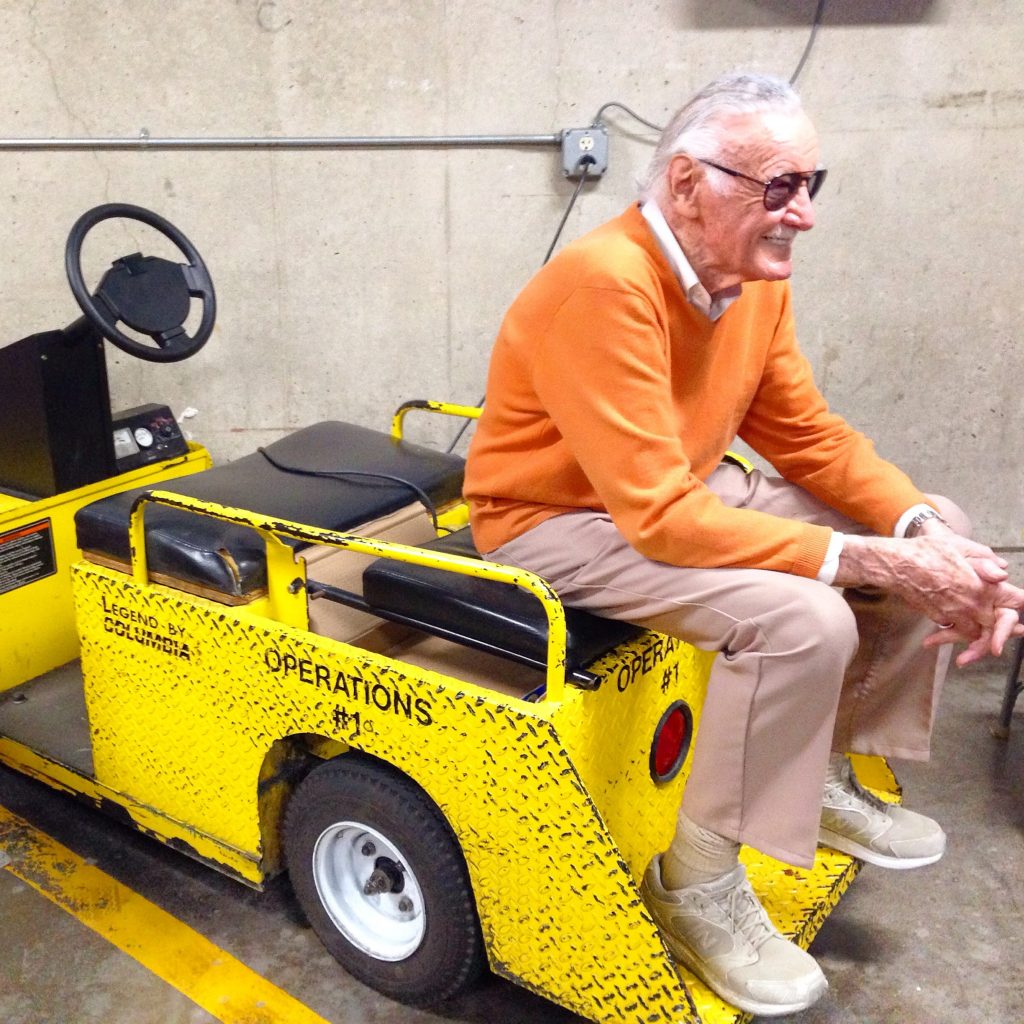 Stan Lee sits on a yellow cart backstage at San Diego Comic Con