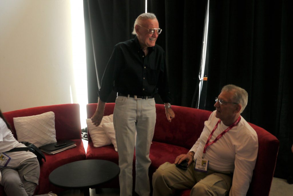 Stan Lee standing, looking excited, in a room at San Diego Comic Con